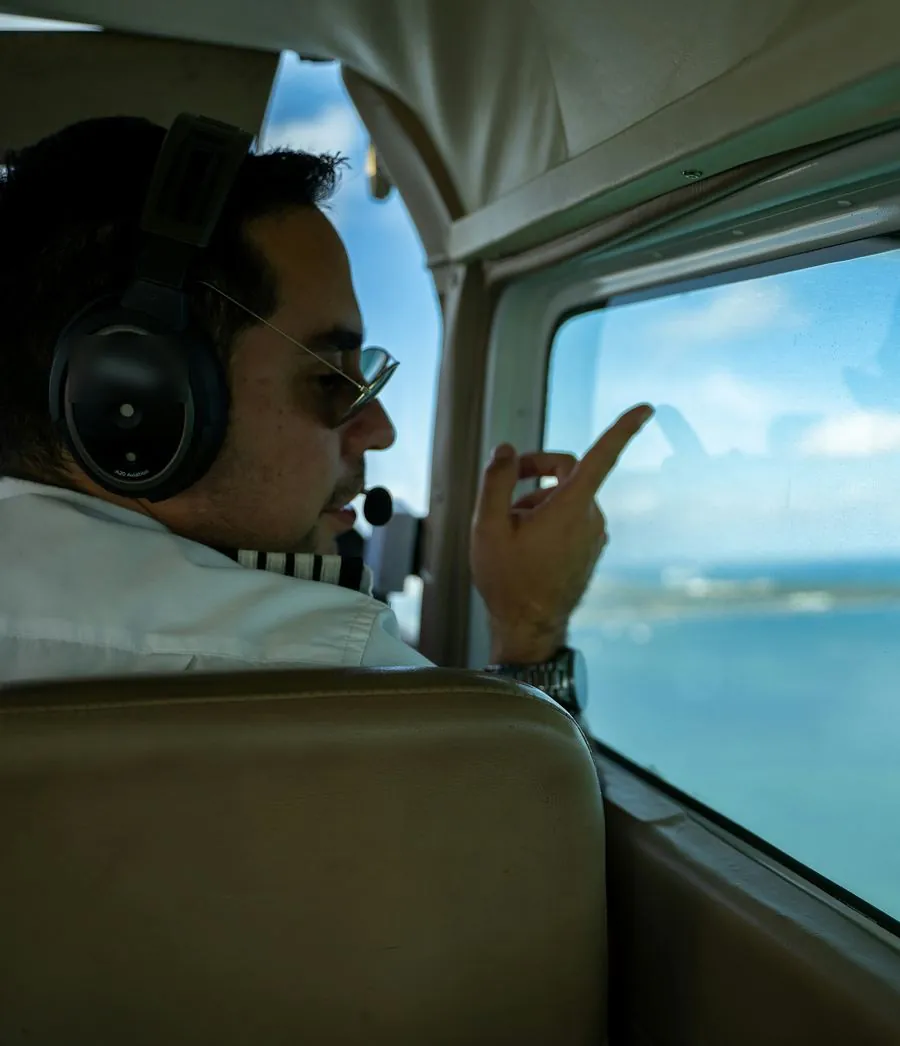 Un pilote d'avion, casque sur les oreilles, regarde par le hublot en vol