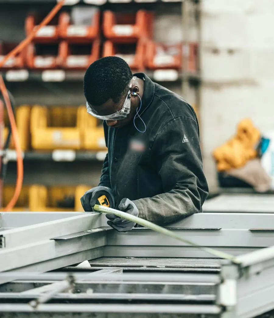 Un technicien avec une oreillette mesure une structure métallique dans un atelier